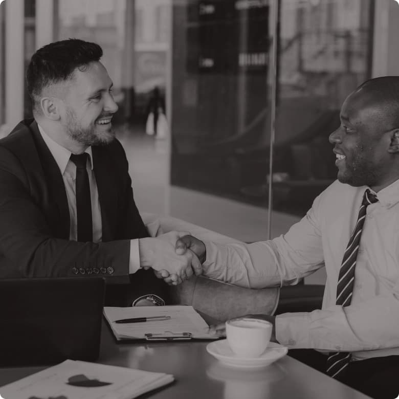 An agent and a client shaking hands across a desk
