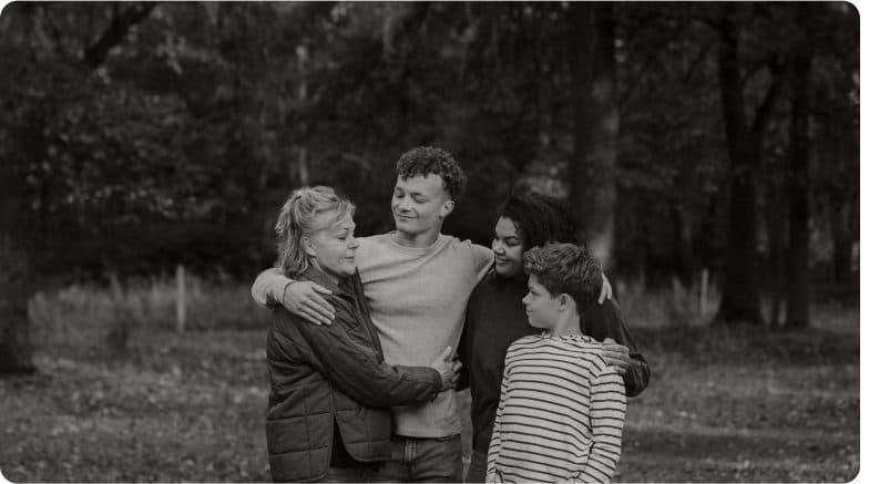A family embracing outdoors among trees