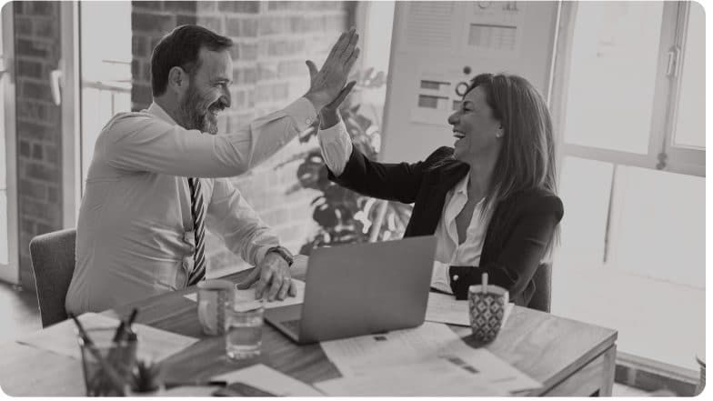Two colleagues celebrating with a high five at a desk